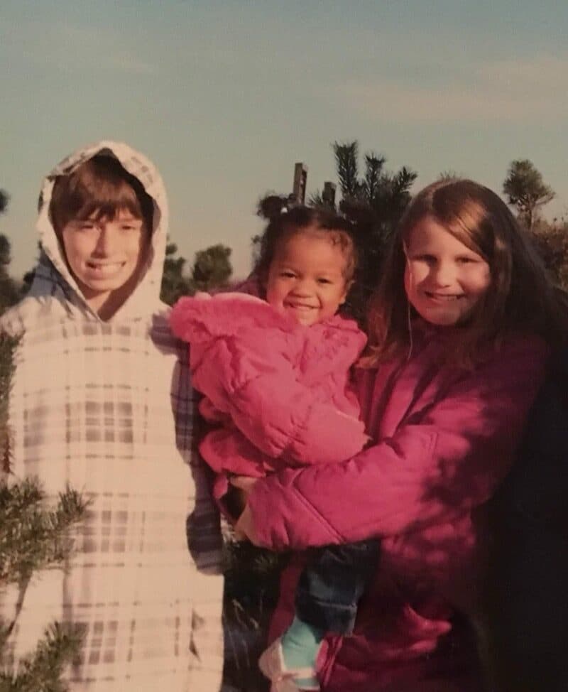 Caleb and Janie as kids, with Janie holding a little girl in a pink jacket.